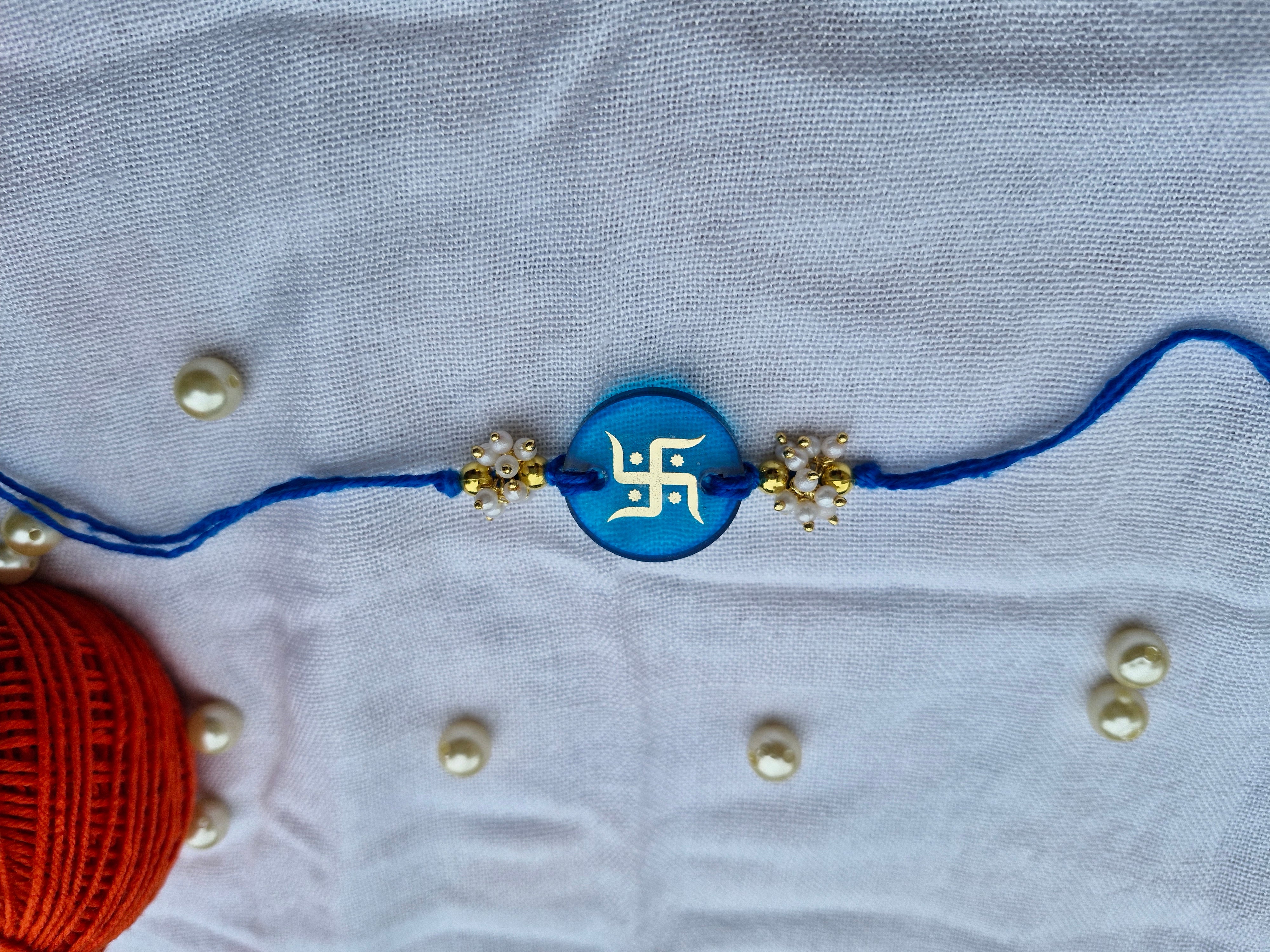 Sacred Swastik Rakhi – Sky Blue Resin with Pearl Cluster Beads