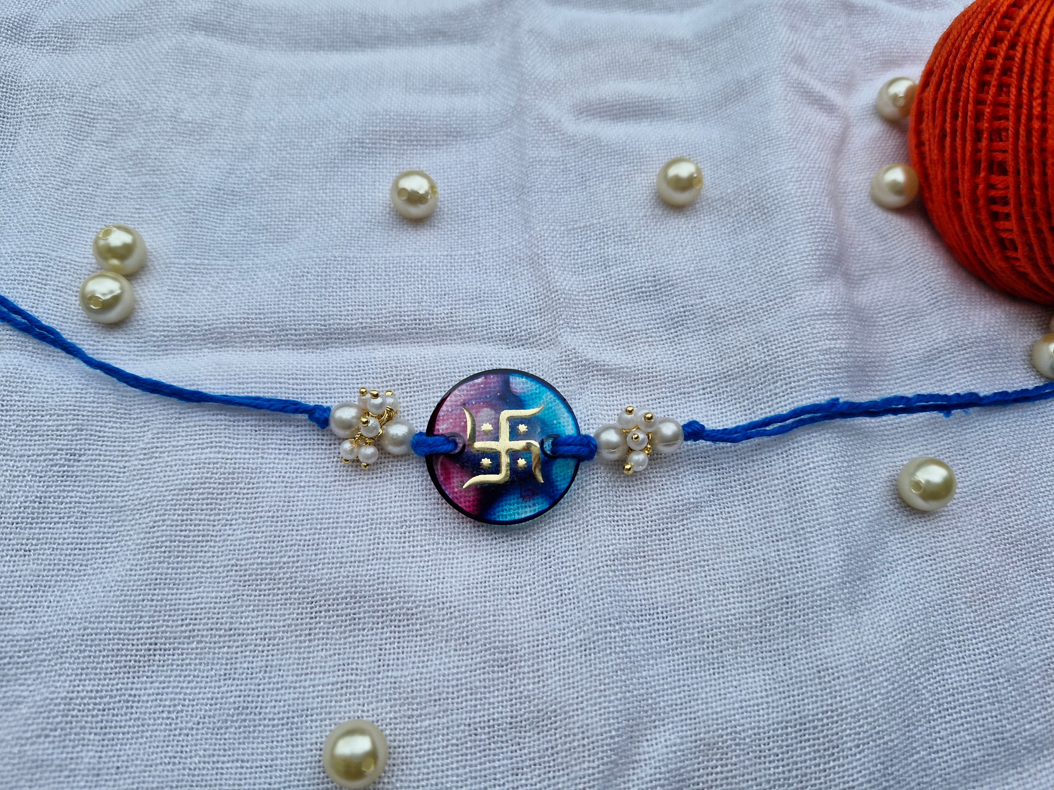 Divine Swastik Rakhi – Resin Center with Blue Thread & Pearl Beads