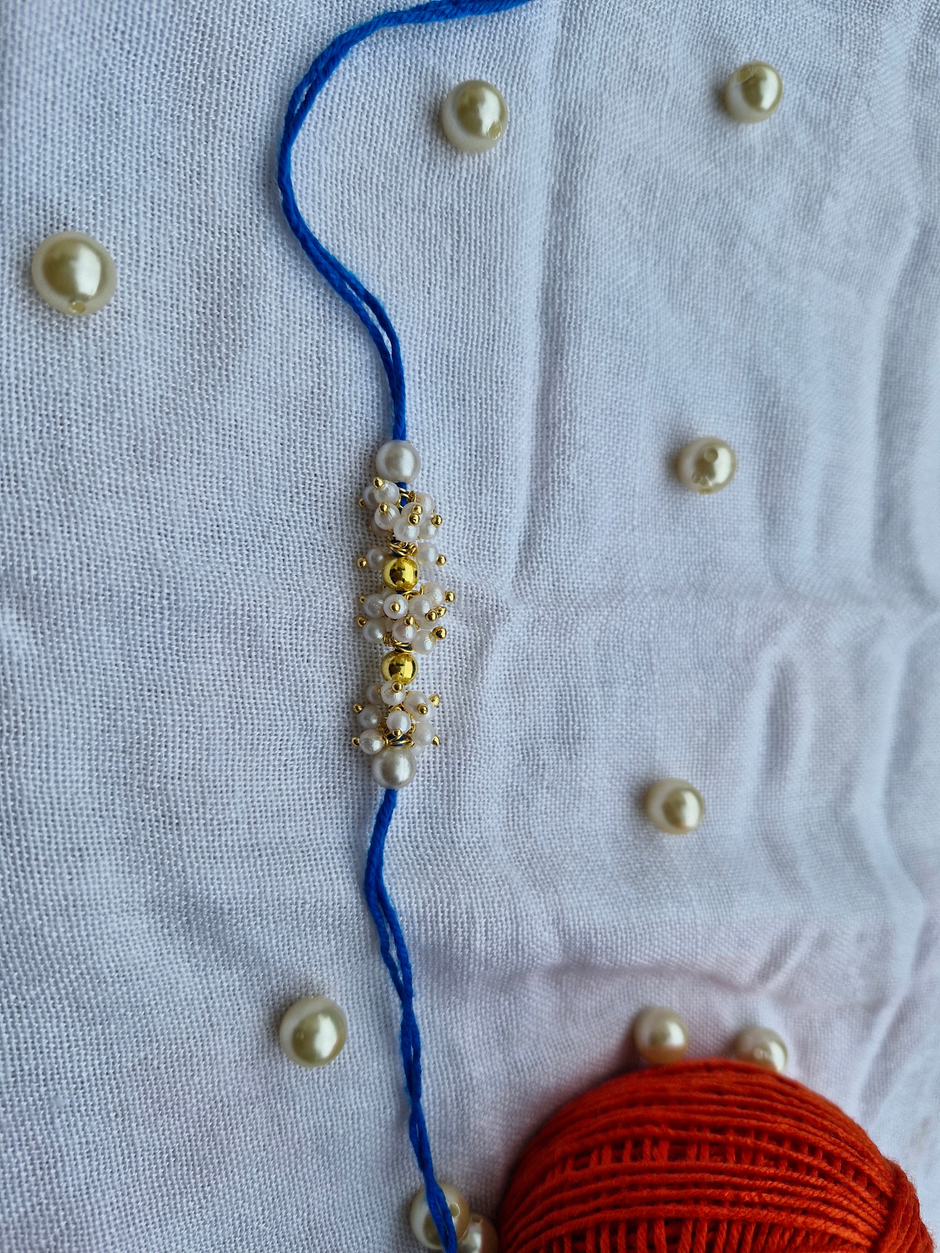 Royal Pearl Cluster Rakhi – Blue Thread with Gold Accents