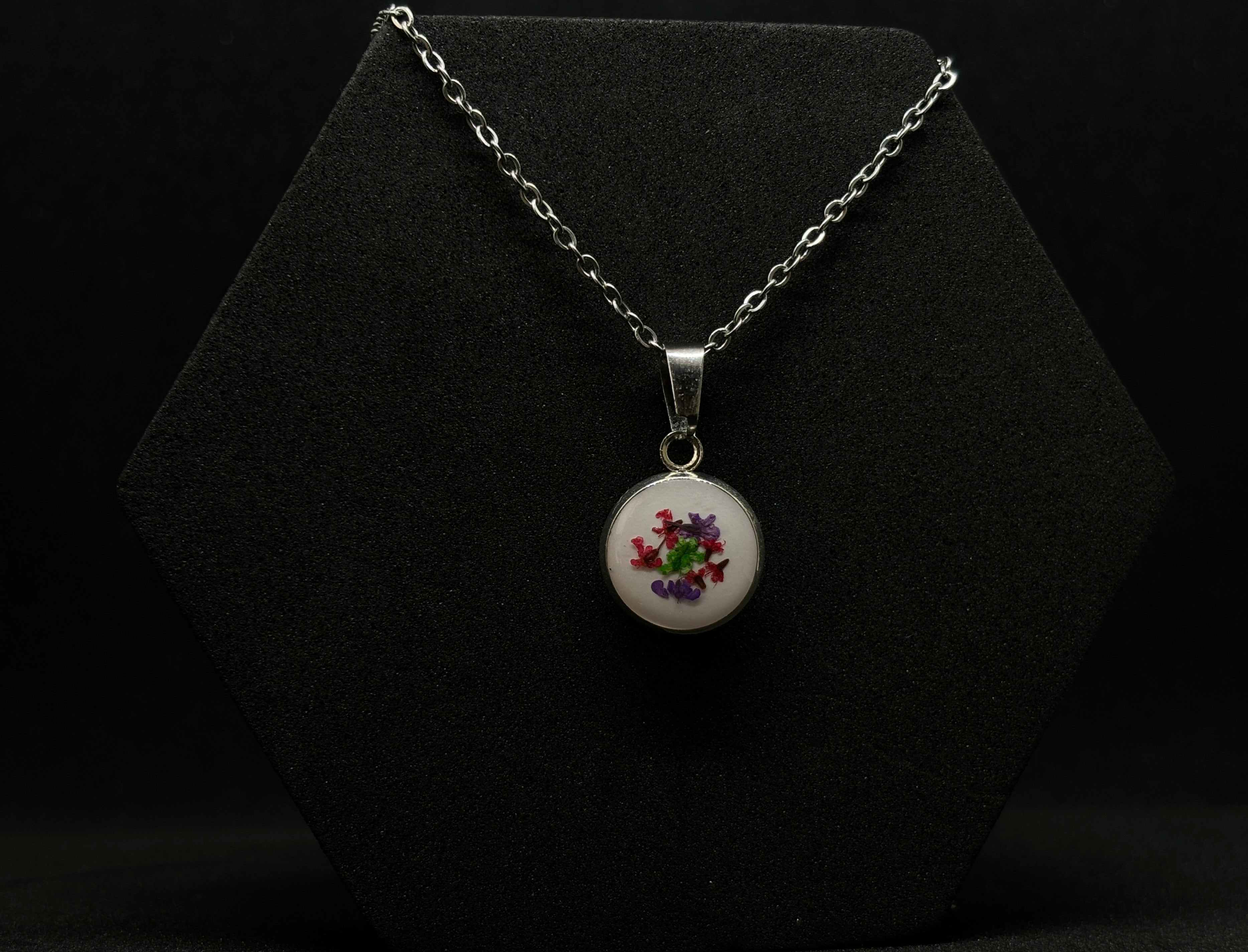 Sterling silver necklace featuring a round resin pendant with vibrant floral inclusions