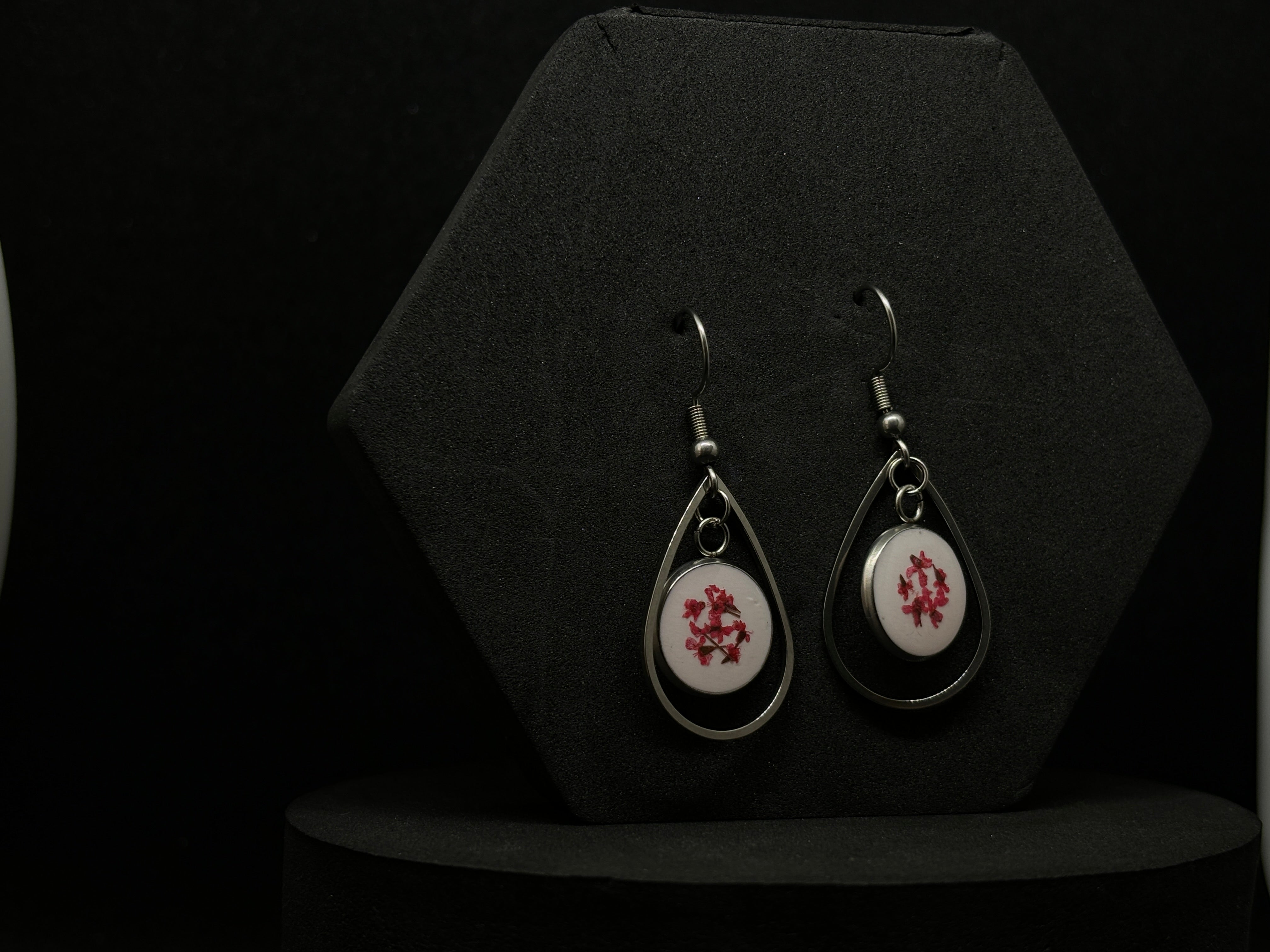 Elegant silver-tone drop earrings featuring vibrant red floral designs encapsulated in clear resin