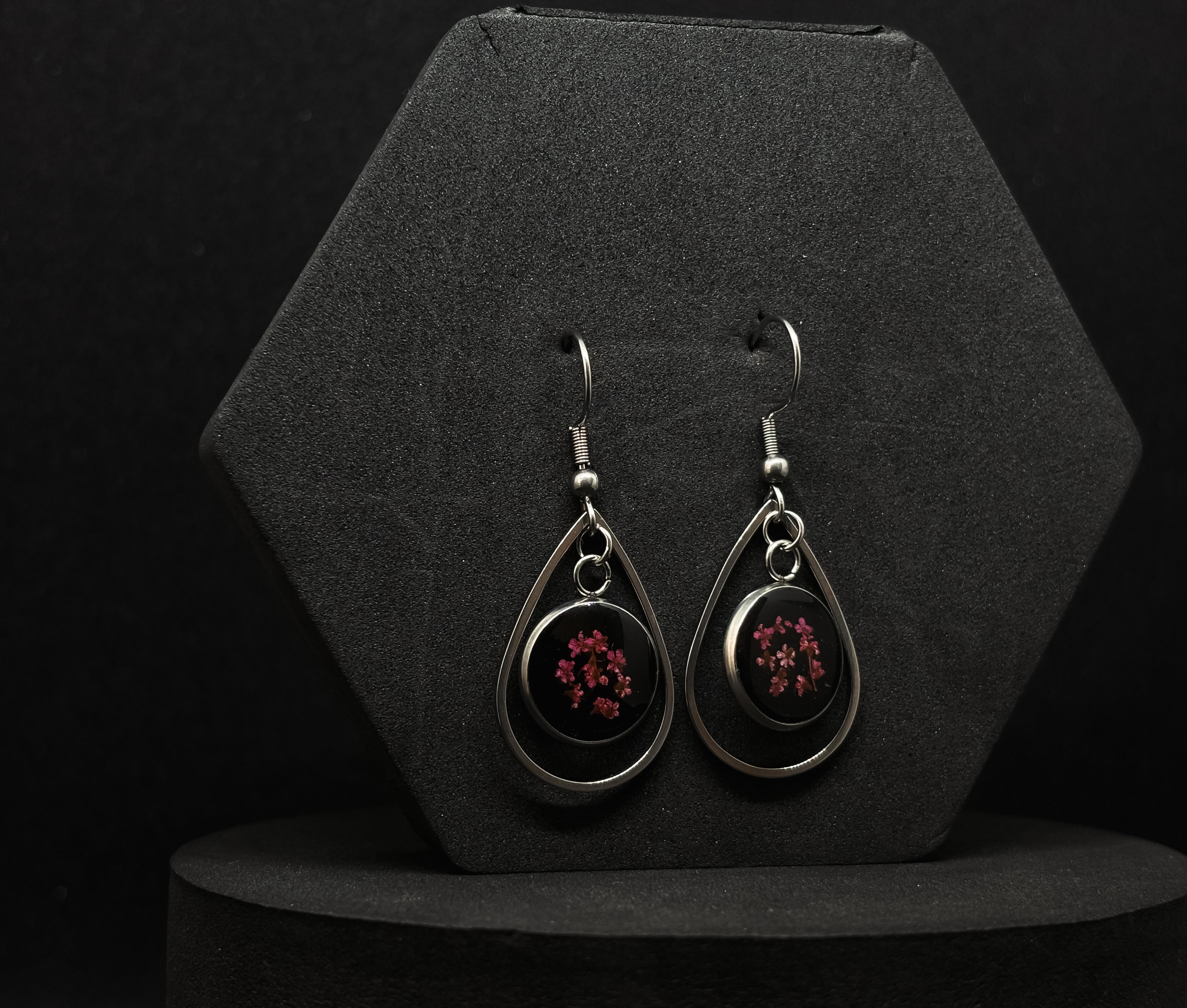 Elegant drop earrings featuring dark red flowers encapsulated in clear resin within a silver-tone teardrop frame