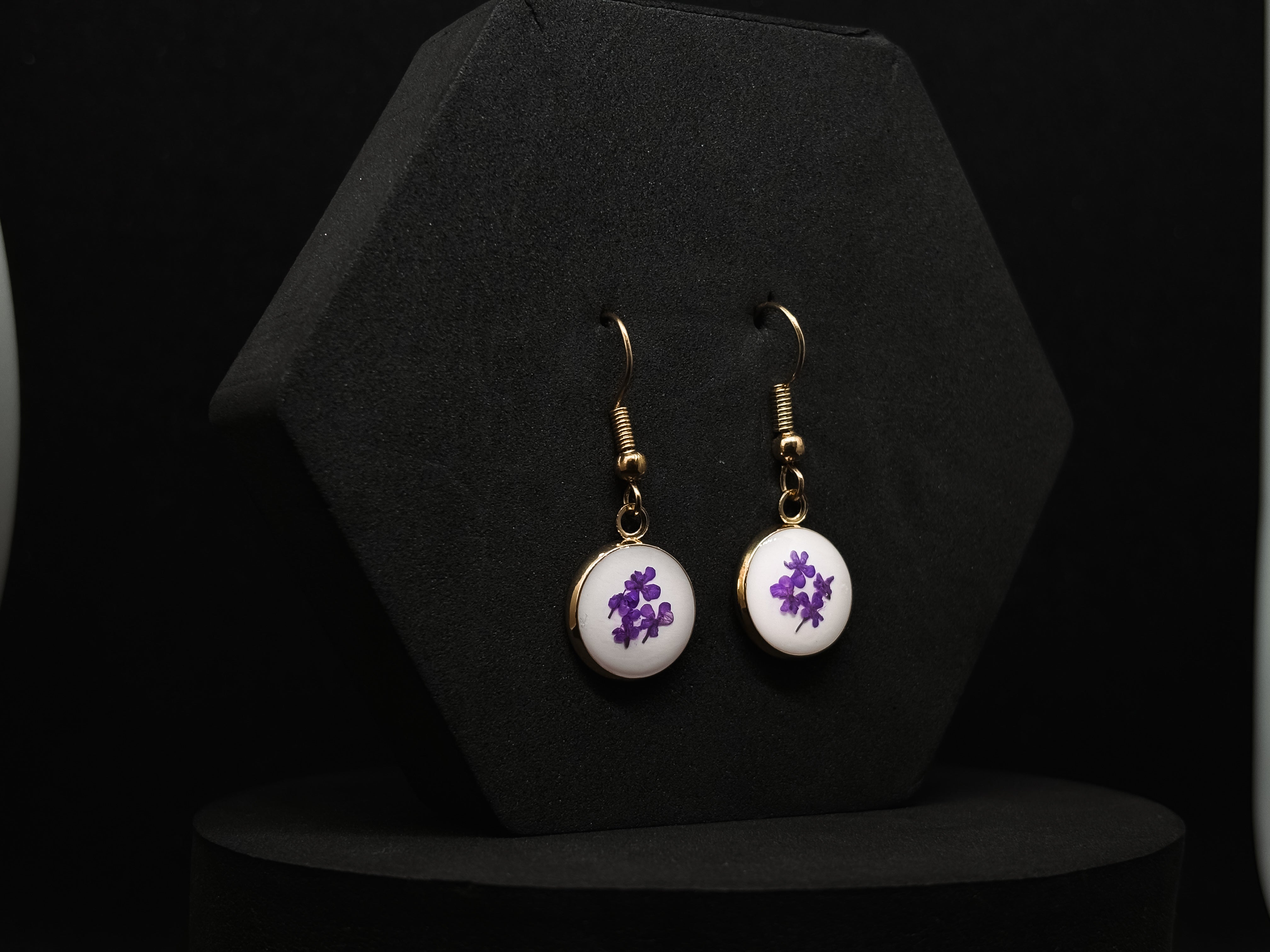 Simple gold-tone drop earrings featuring clear resin circles with vibrant purple flowers inside